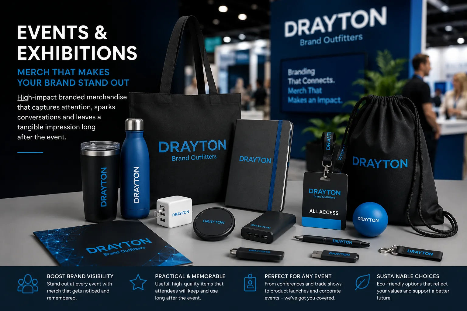 A collection of branded Drayton merchandise displayed on a table at an event booth, including a tote bag, tumbler, notebook, lanyard, wrist strap, ball, mouse pad, and other accessories, with a large Drayton backdrop behind them.